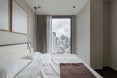 Modern bedroom with city view from large window, featuring elegant decor and cozy bedding.