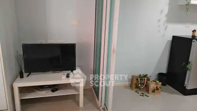 Modern living room with TV and sliding glass door leading to kitchen area.