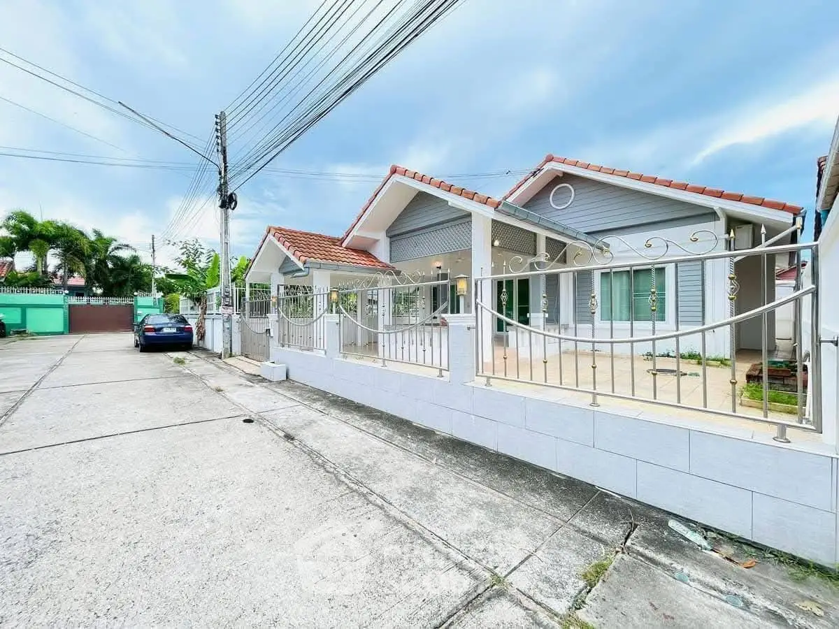 Charming suburban house with red-tiled roof and gated front yard in a peaceful neighborhood.
