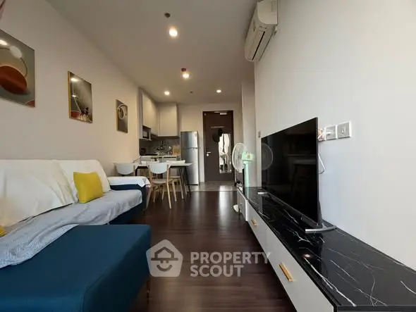 Modern living room with open kitchen, stylish decor, and sleek furniture in a cozy apartment.