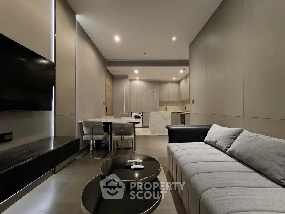 Modern living room with sleek design and open kitchen layout, featuring contemporary furniture and ambient lighting.