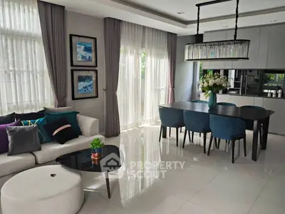 Elegant modern living room with stylish decor and dining area, featuring large windows and chic furniture.