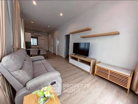 Modern living room with cozy sofa and TV unit, open layout to dining area, bright and inviting space.
