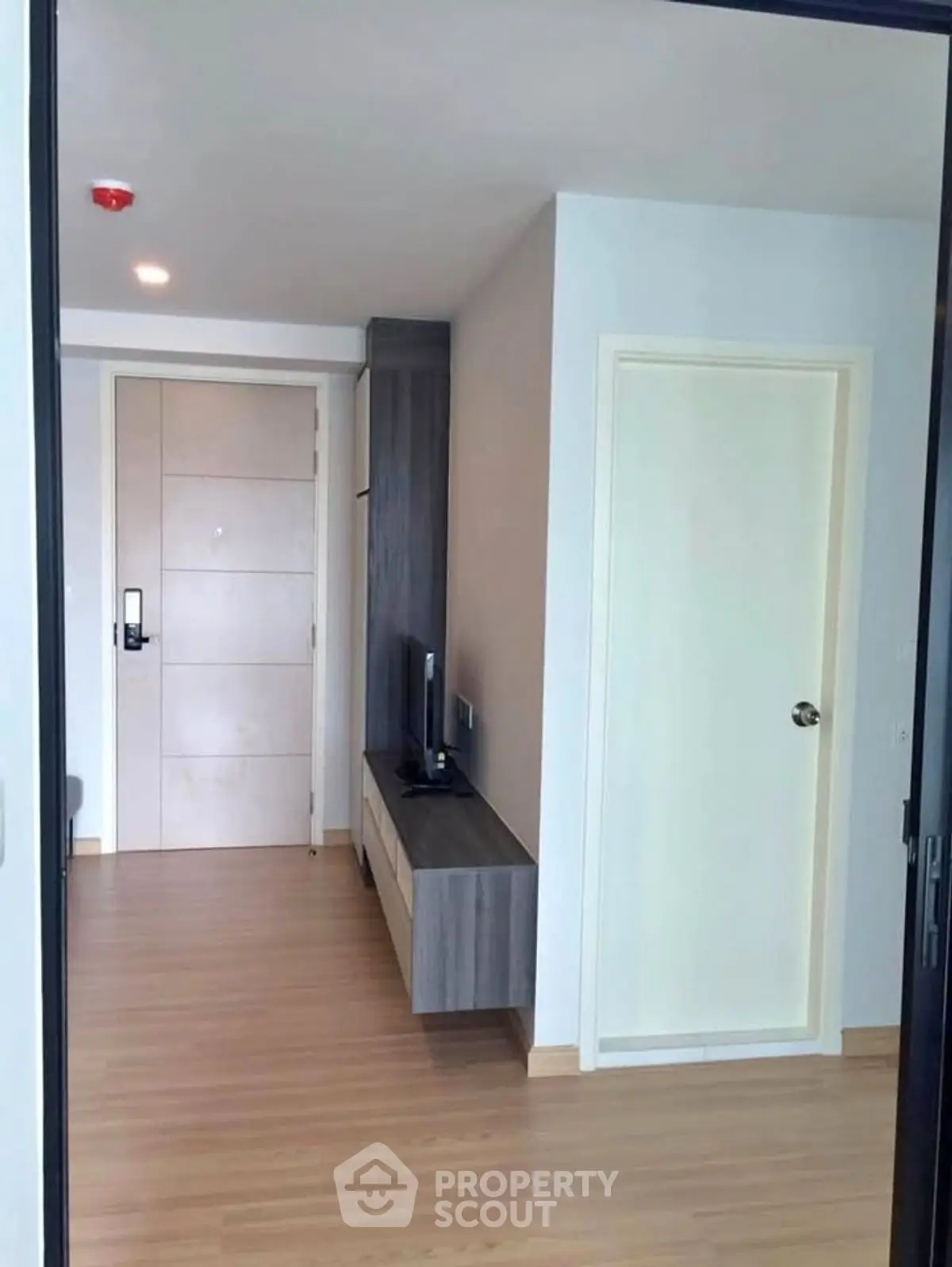 Modern apartment entrance with sleek wooden flooring and stylish TV console.