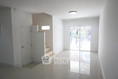 Spacious and bright living room with modern staircase and large windows.