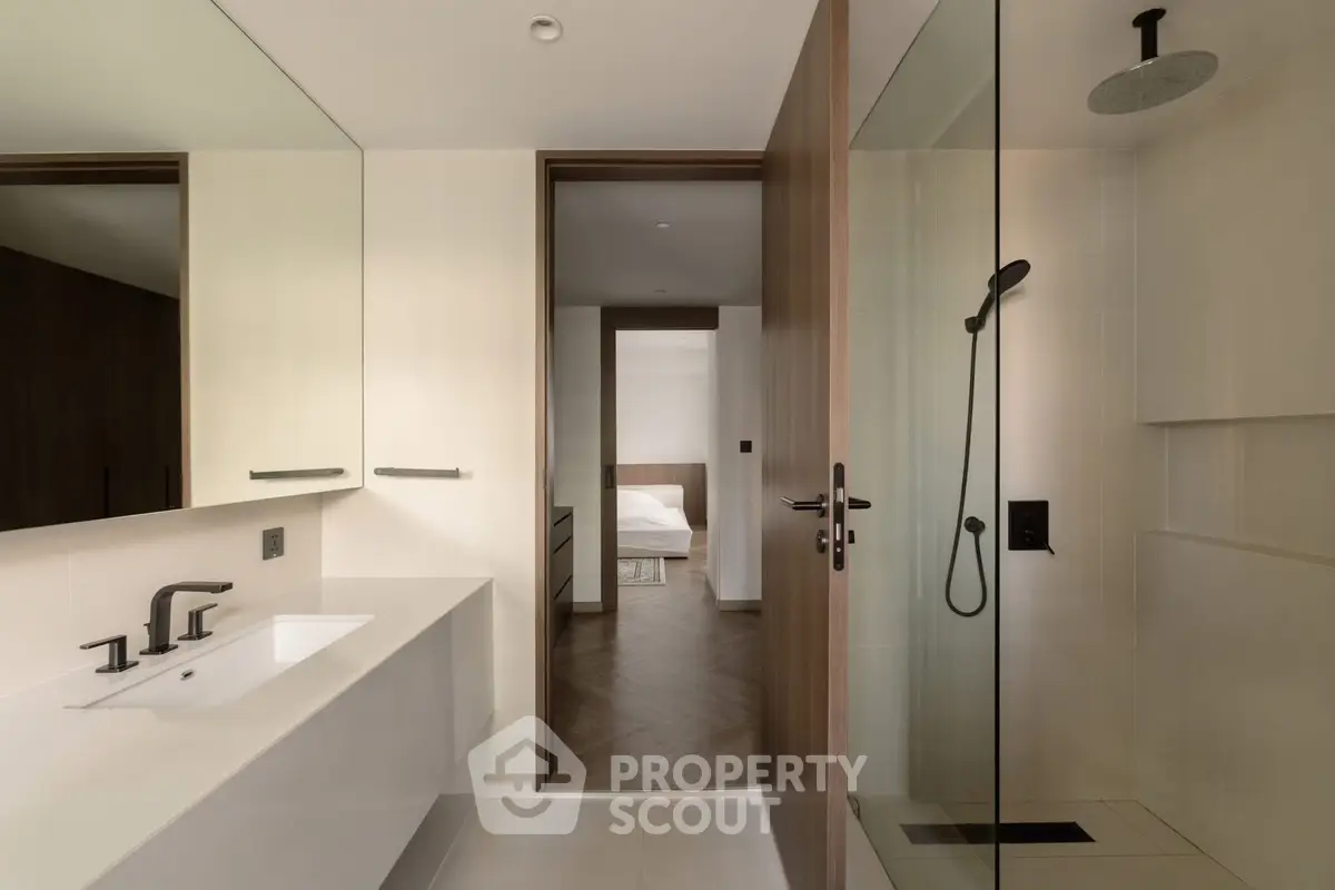 Modern bathroom with sleek fixtures and view into a stylish bedroom