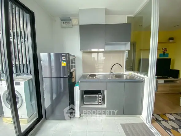 Modern compact kitchen with sleek appliances and washing machine in a bright apartment.