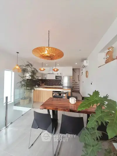 Modern open-plan kitchen and dining area with stylish lighting and wooden accents