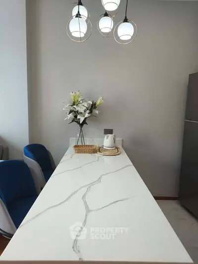 Modern kitchen with elegant marble countertop and stylish pendant lights.