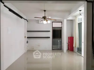 Spacious empty room with ceiling fan and shelves, ideal for customization.