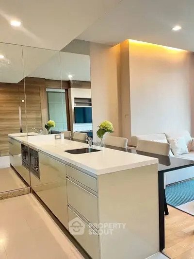 Modern open-layout kitchen with sleek design and integrated appliances, leading to a cozy living area.