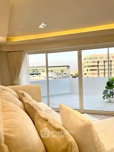 Luxurious living room with large windows and balcony offering stunning city views.