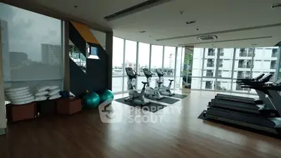 Spacious gym with modern equipment and city view in luxury apartment building.