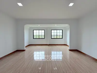 Spacious empty room with large windows and polished wooden floors, perfect for customization.