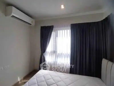 Cozy bedroom with natural light and air conditioning, perfect for relaxation.