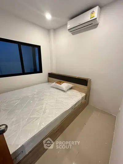 Cozy bedroom with modern air conditioning and natural light from window, perfect for relaxation.