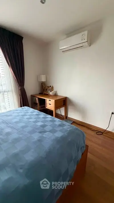Cozy bedroom with modern furniture and air conditioning, featuring a large window with elegant curtains.