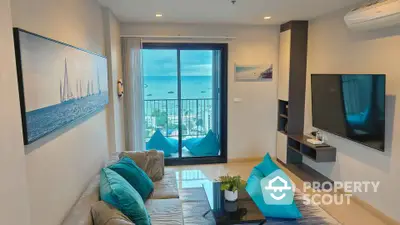 Modern living room with ocean view, stylish decor, and large TV in a high-rise apartment.