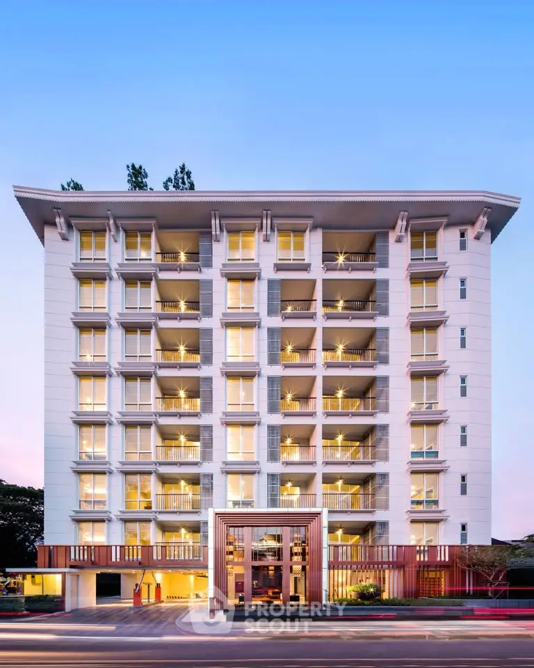 Modern multi-story residential building with elegant facade and well-lit balconies at dusk.