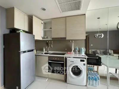 Modern kitchen with appliances including washing machine and oven, open layout to living area.