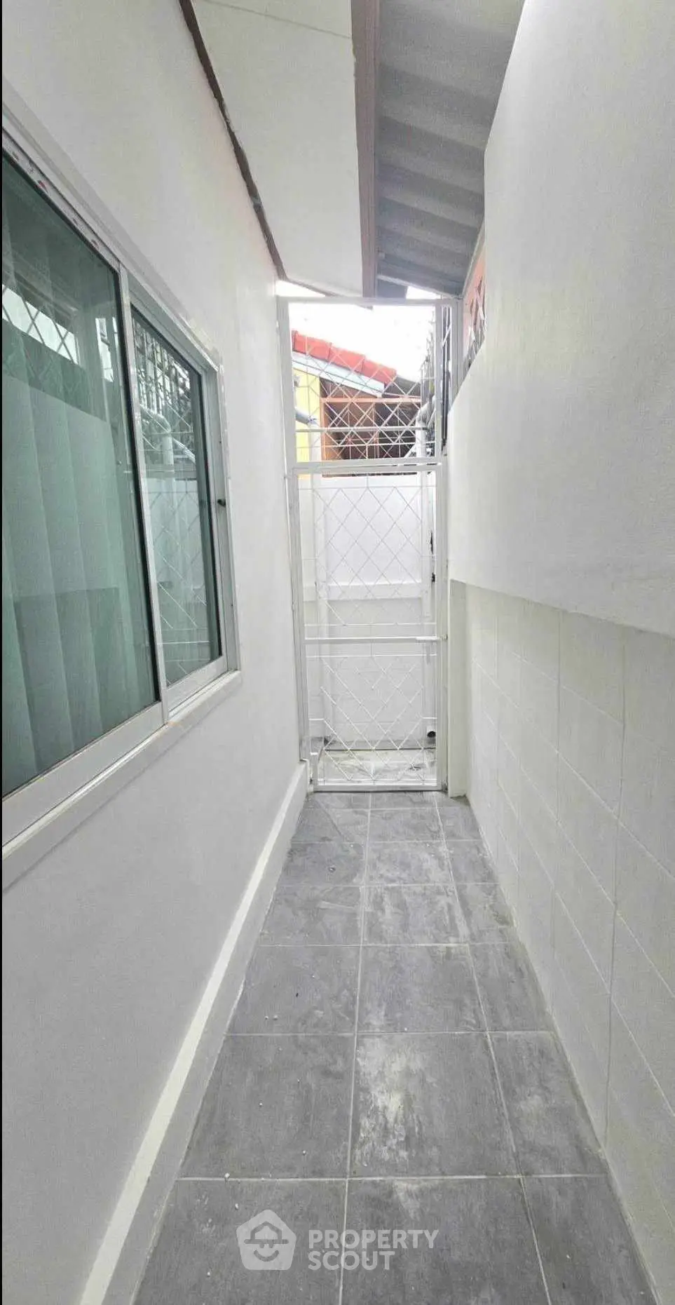 Narrow exterior passageway with tiled floor and gated entrance