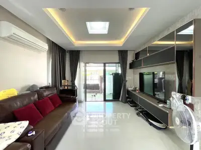 Modern living room with sleek design, large sofa, and entertainment center, featuring a skylight and sliding glass doors.