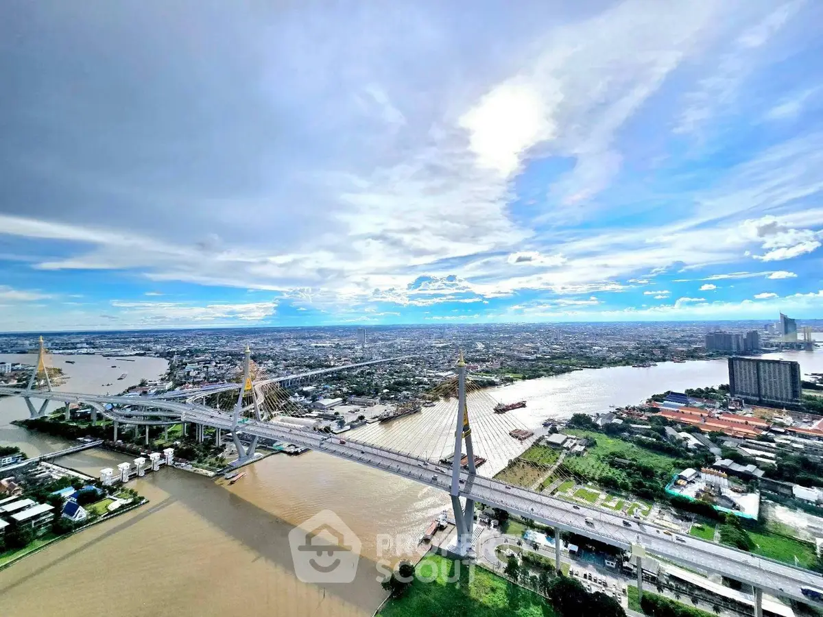Stunning aerial view of cityscape with river and iconic bridge under a vibrant sky.