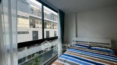 Modern bedroom with large window offering urban view and stylish bedding