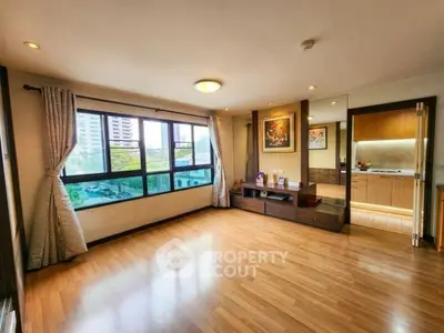 Spacious living room with wooden flooring and large windows offering city views.