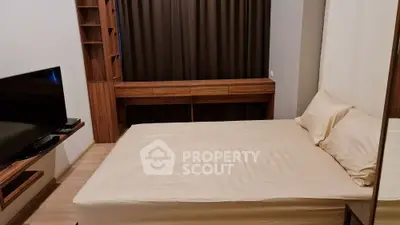 Cozy bedroom with modern wooden furniture and large TV, perfect for relaxation.