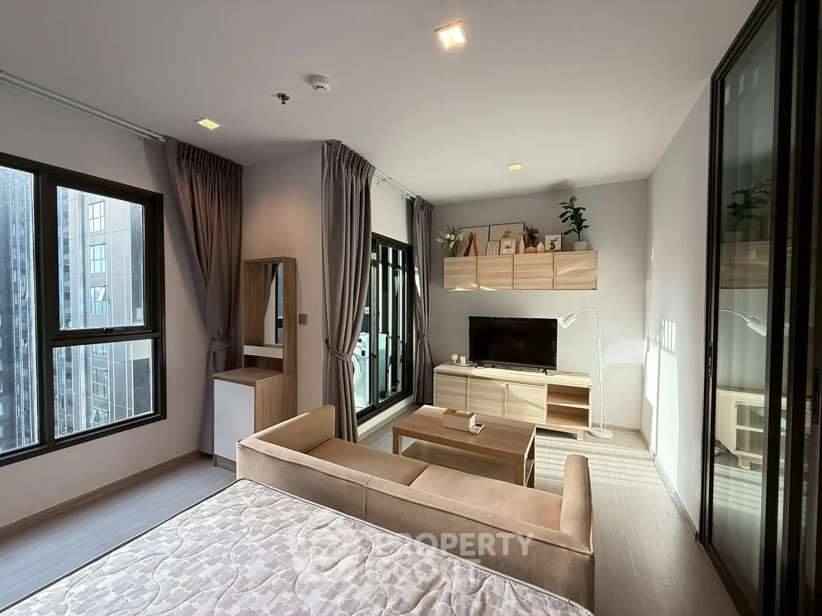 Modern living room with cozy sofa, TV, and large windows in a stylish apartment.