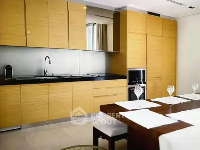 Modern kitchen with sleek wooden cabinets and dining area, featuring built-in oven and minimalist design.