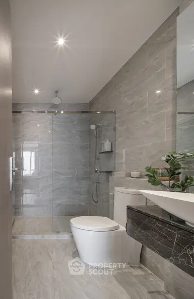 Luxurious modern bathroom with sleek marble tiles and glass shower enclosure.