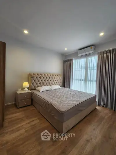 Spacious bedroom with elegant decor and natural light, featuring a plush bed and wooden flooring.
