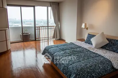 Spacious bedroom with large windows and city view, featuring elegant wooden flooring and modern decor.
