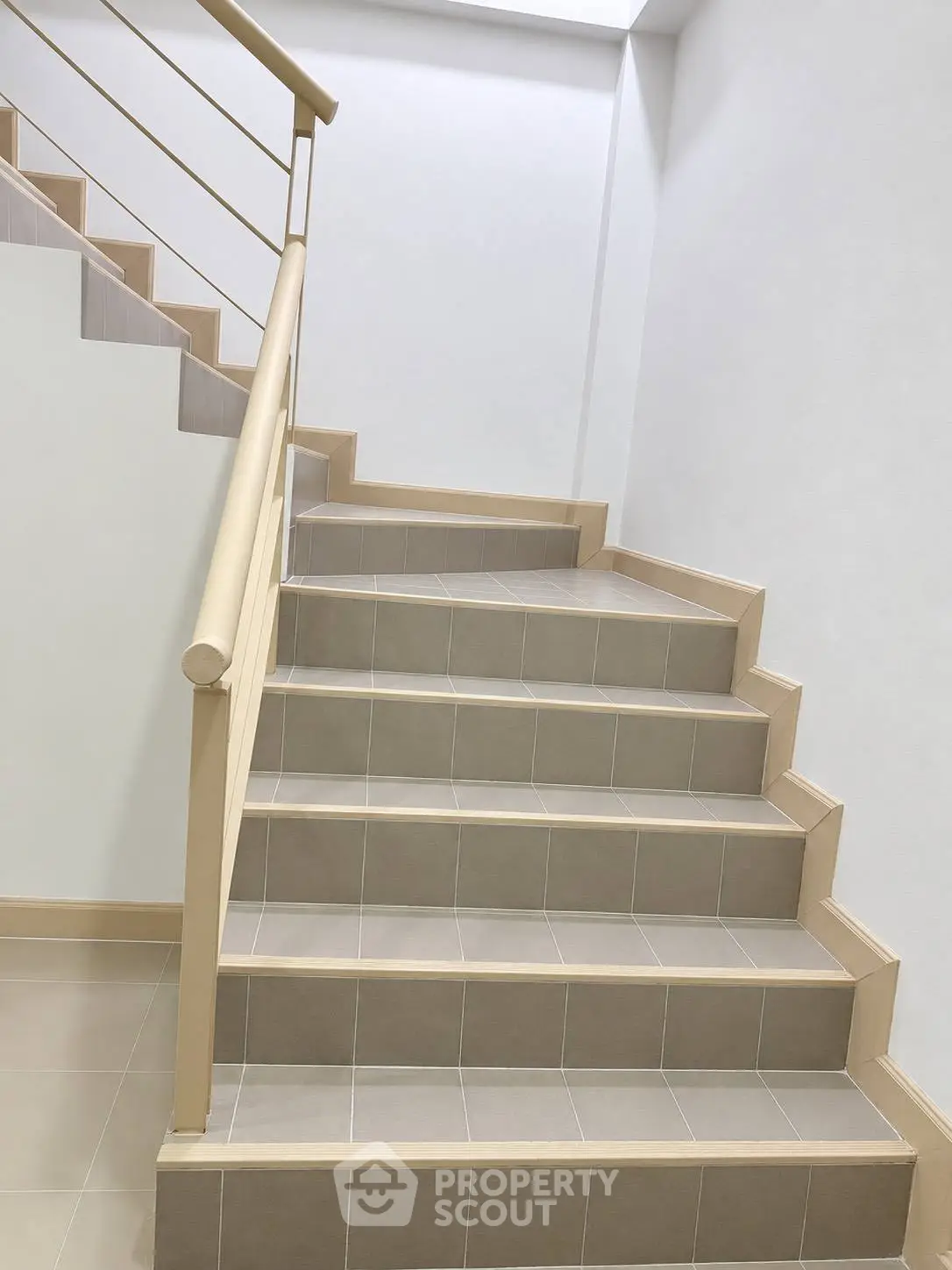 Modern staircase with beige tiles and sleek railing in a contemporary building.