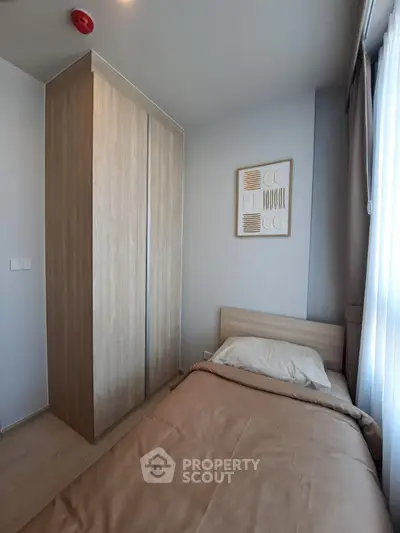 Cozy small bedroom with wooden wardrobe and single bed, perfect for minimalist living.