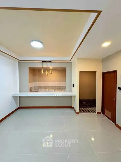 Spacious modern living room with elegant ceiling lights and tiled flooring.