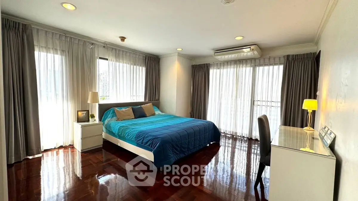 Spacious bedroom with elegant decor and large windows offering ample natural light.