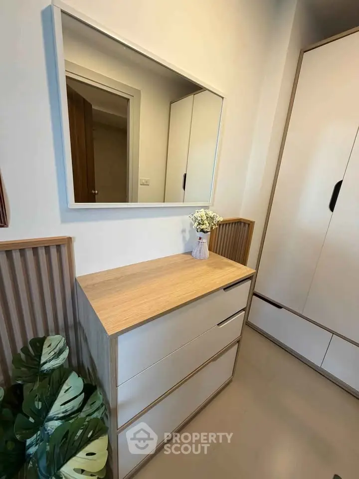 Modern bedroom with sleek dresser and large mirror, featuring minimalist design and elegant decor.