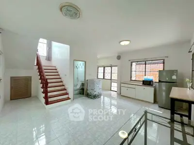 Spacious open-plan living area with staircase and modern kitchen appliances