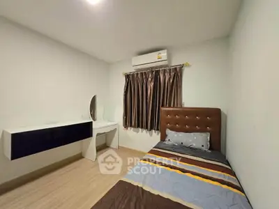 Cozy bedroom with single bed, air conditioning, and modern vanity in minimalist design.