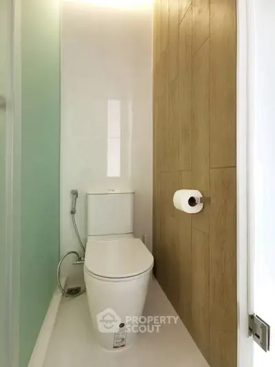 Modern minimalist bathroom with sleek toilet and wood accent wall.