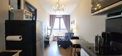 Modern living room with open kitchen, featuring sleek appliances and cozy seating area with natural light.