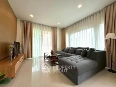 Modern living room with large sectional sofa and floor-to-ceiling windows