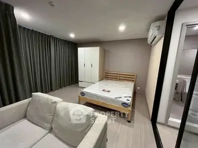 Spacious bedroom with modern furnishings and natural light, featuring a cozy sofa and large wardrobe.