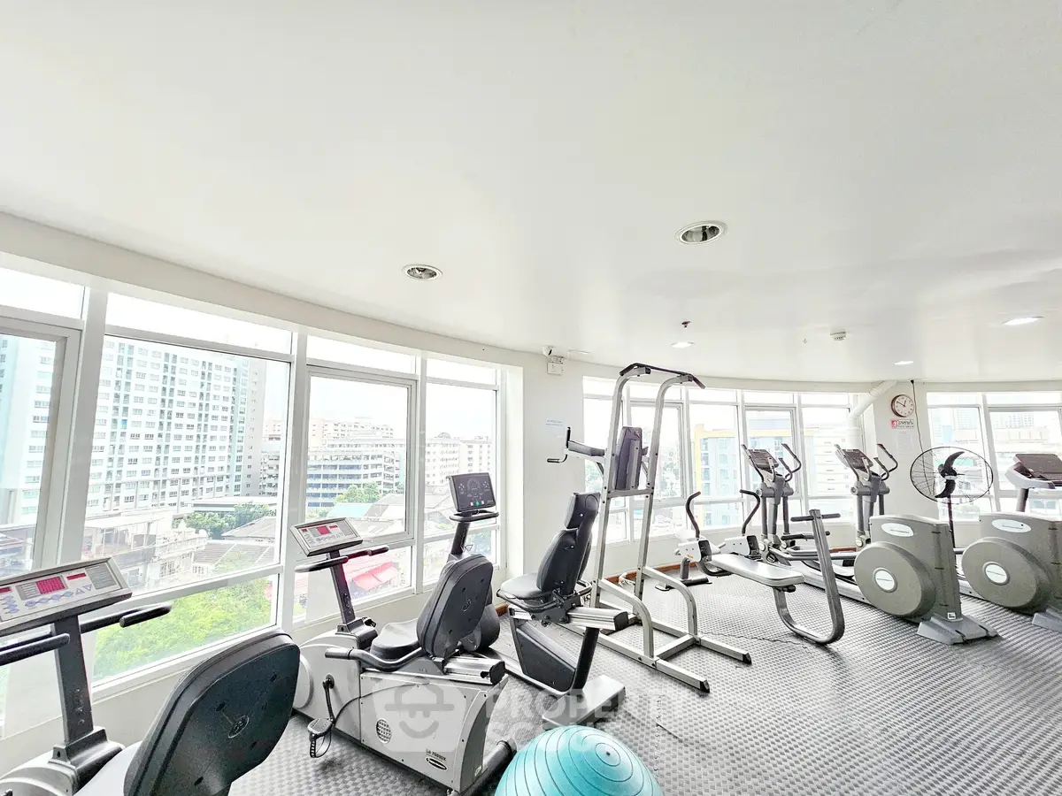Spacious gym with modern equipment and city view, ideal for fitness enthusiasts.