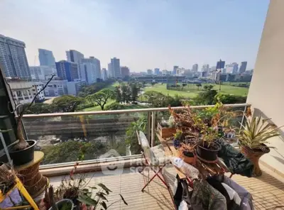 Spacious balcony with lush greenery and stunning city skyline view, perfect for relaxation and urban living.