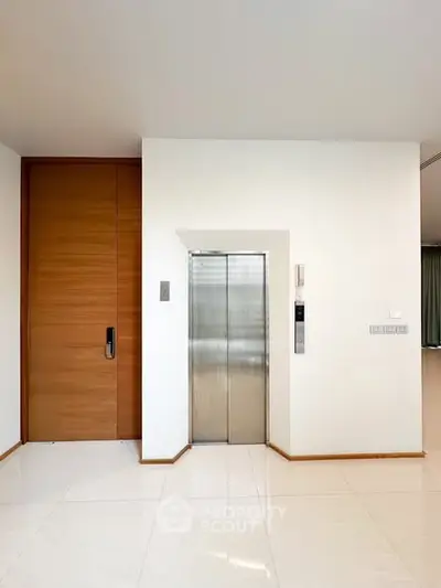 Modern interior with sleek elevator and wooden door, perfect for luxury living.