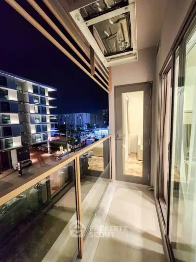 Modern balcony with city view, glass railing, and sleek design at night.